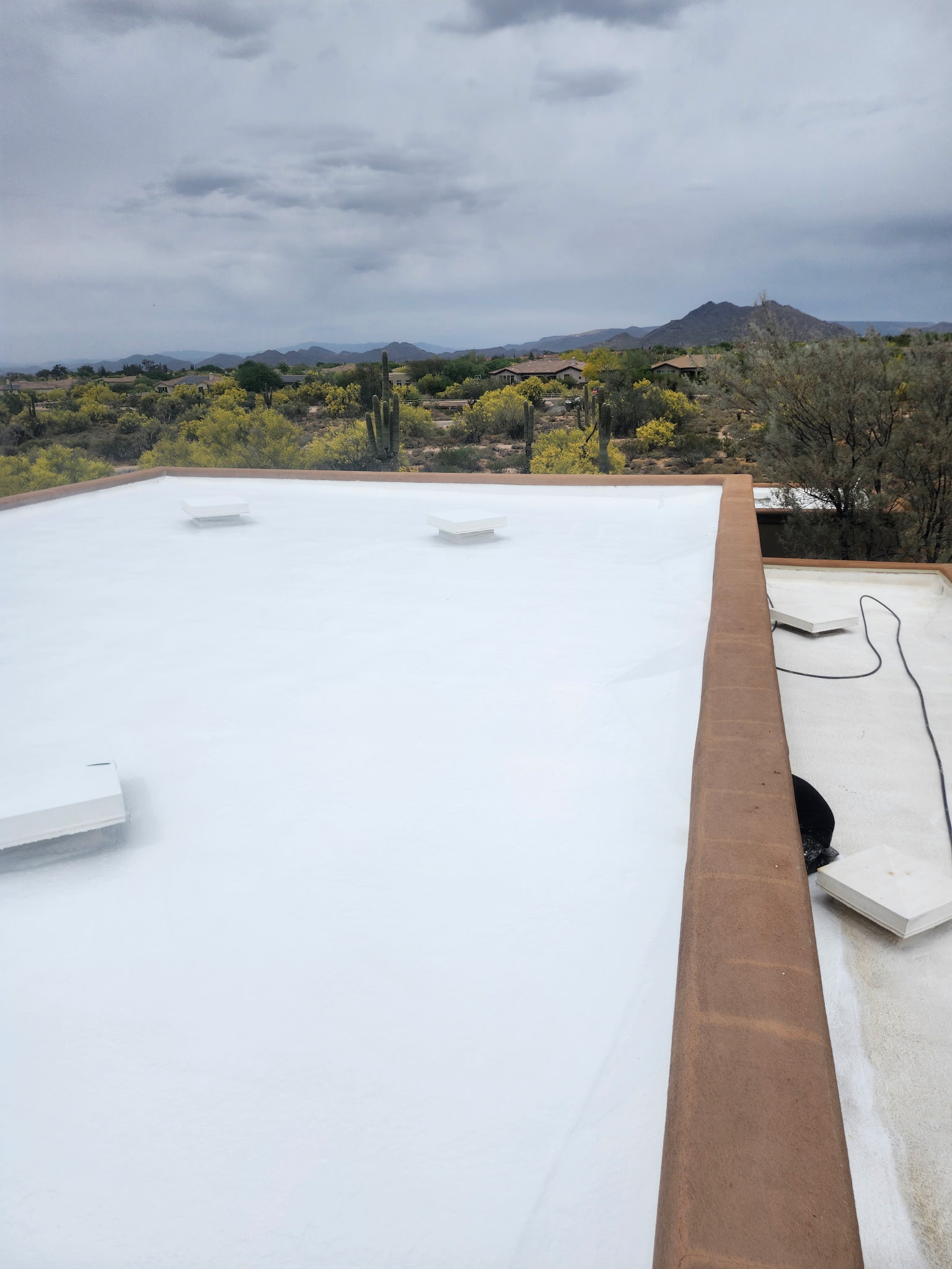 Foam flat roof with skylights under cloudy monsoon-season skies in North Scottsdale, Arizona.