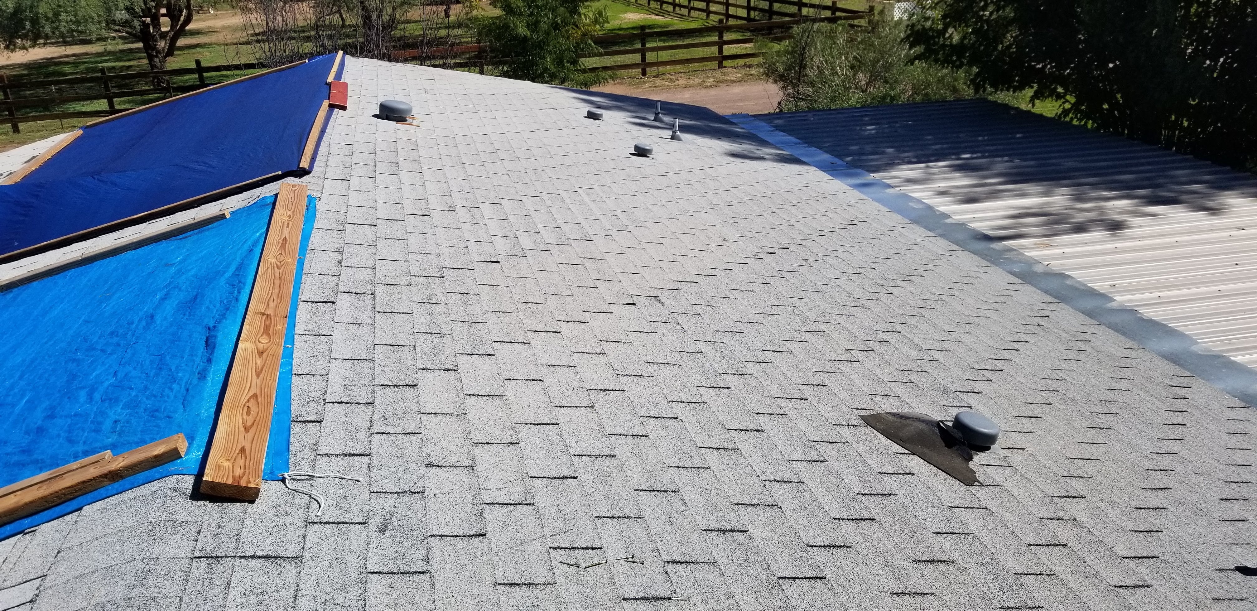 Storm-damaged shingle roof covered with blue tarps during emergency repair in the Phoenix area.