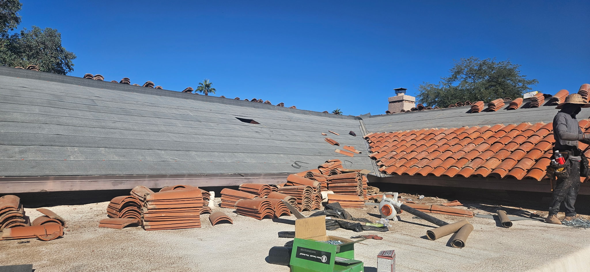 A close-up view of a worn white foam flat roof with significant ponding, organic debris, and multiple skylights in Tempe, Arizona, during an inspection by Duraf
