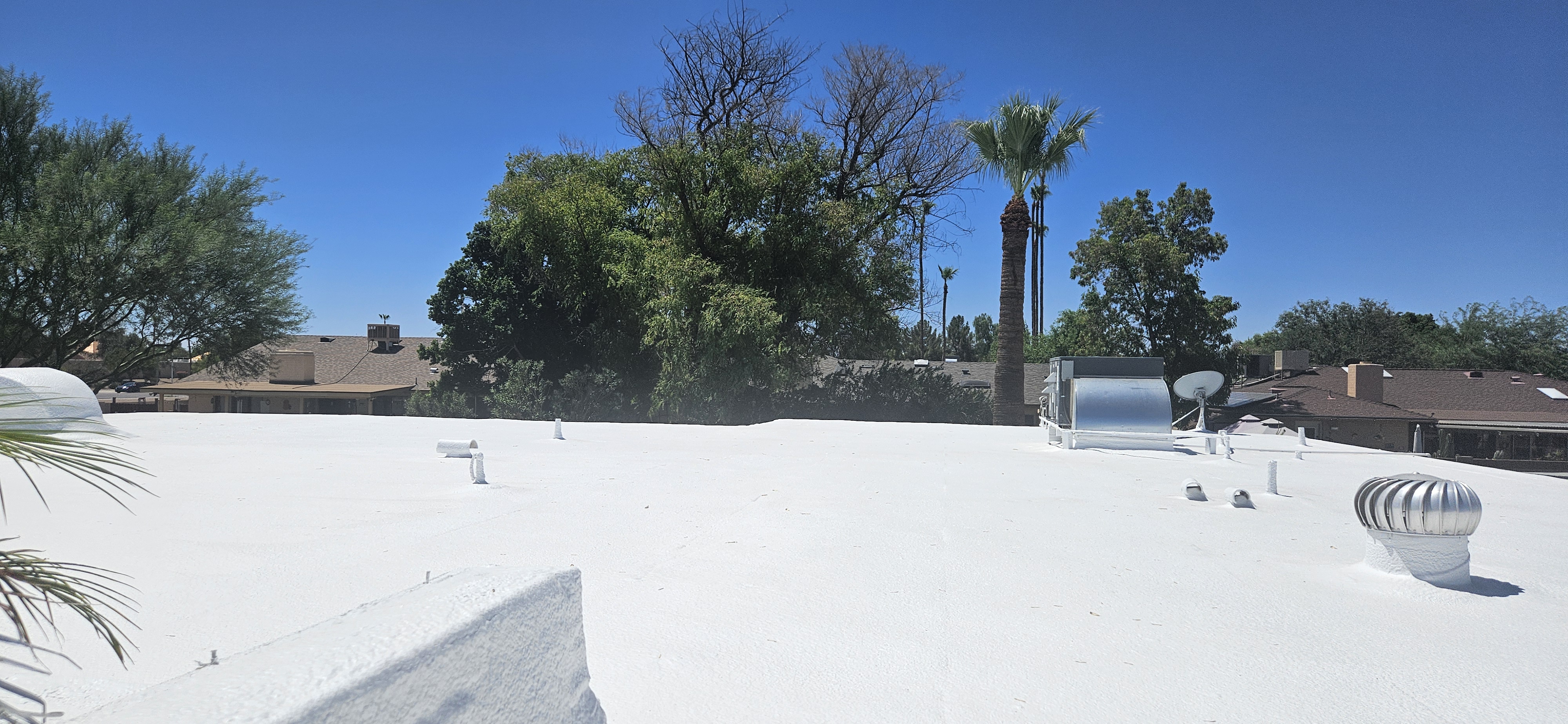 Bright reflective white foam roof in Phoenix — a cool-roof alternative that reduces cooling load like solar.