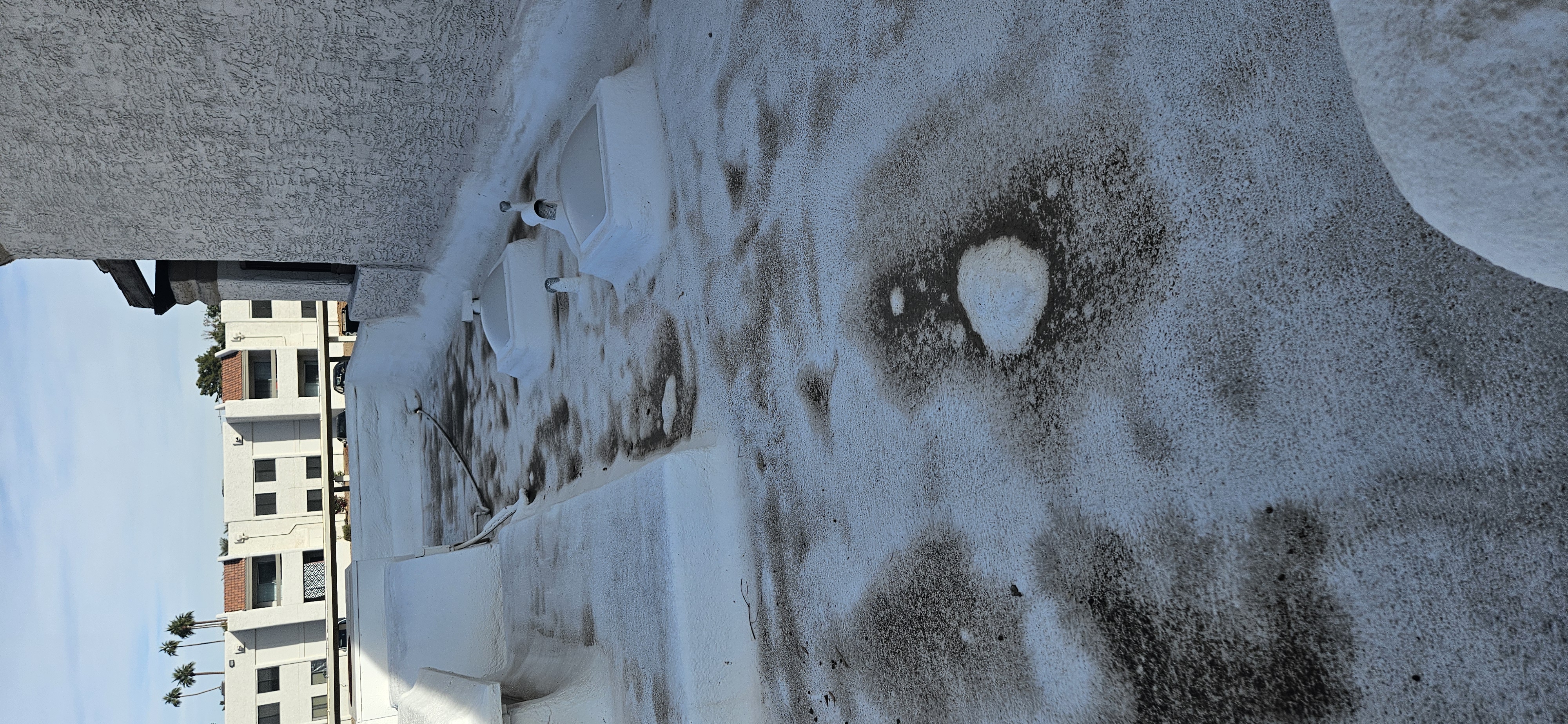 Close-up of a damaged white foam flat roof with cracks and blisters showing early signs of roof damage in Phoenix