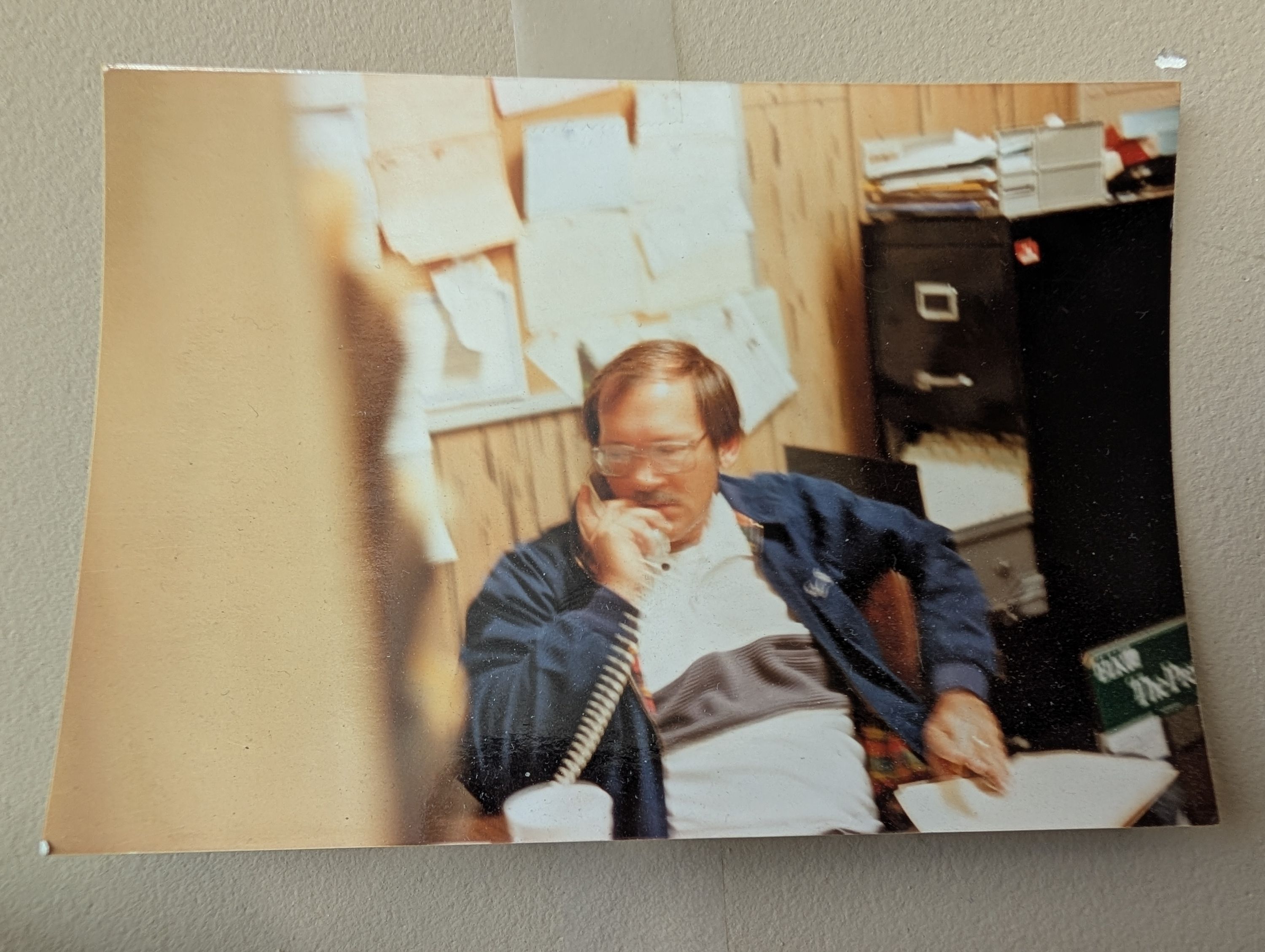 Steve Forstie, the founder of Durafoam Roofing is casually dressed in a collared shirt, dark jacket, and glasses while talking on the phone.