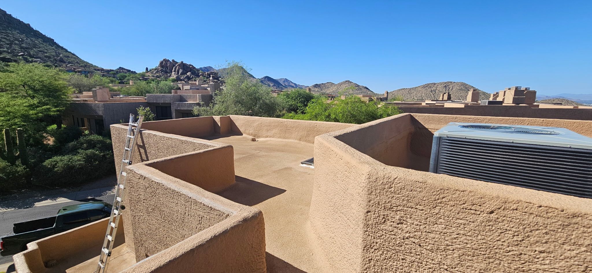 A tan foam roof with parapet walls and an HVAC unit sits on a commercial building in Scottsdale, Arizona, by Durafoam Roofing.